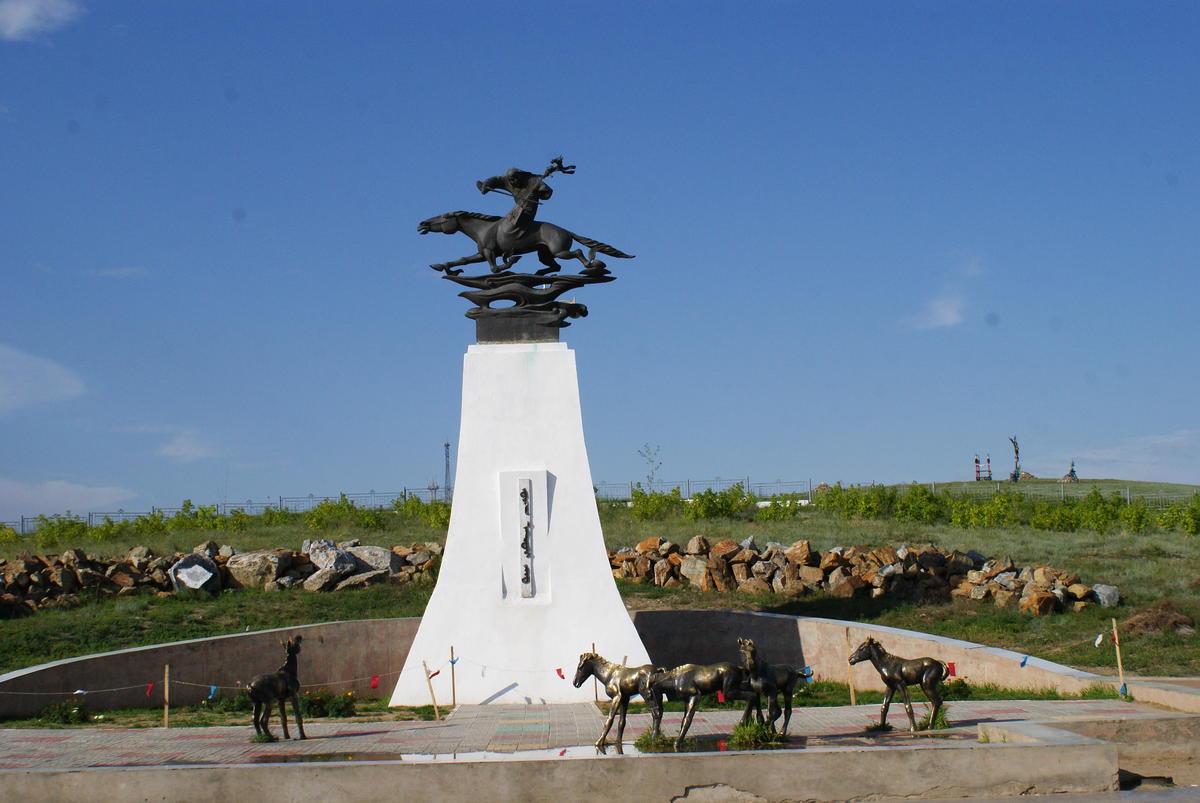 Das Bild zeigt ein großes Denkmal mit  wilden Pferden und einem reitenden Mongolen.
