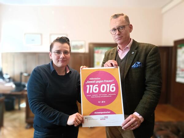 Oberbrgermeister Christian Thieme und Brgermeisterin Kathrin Weber zeigen ein Plakat des Hilfetelefons auf dem die Nummer des kostenlosen Service, die 116016, zu sehen ist.